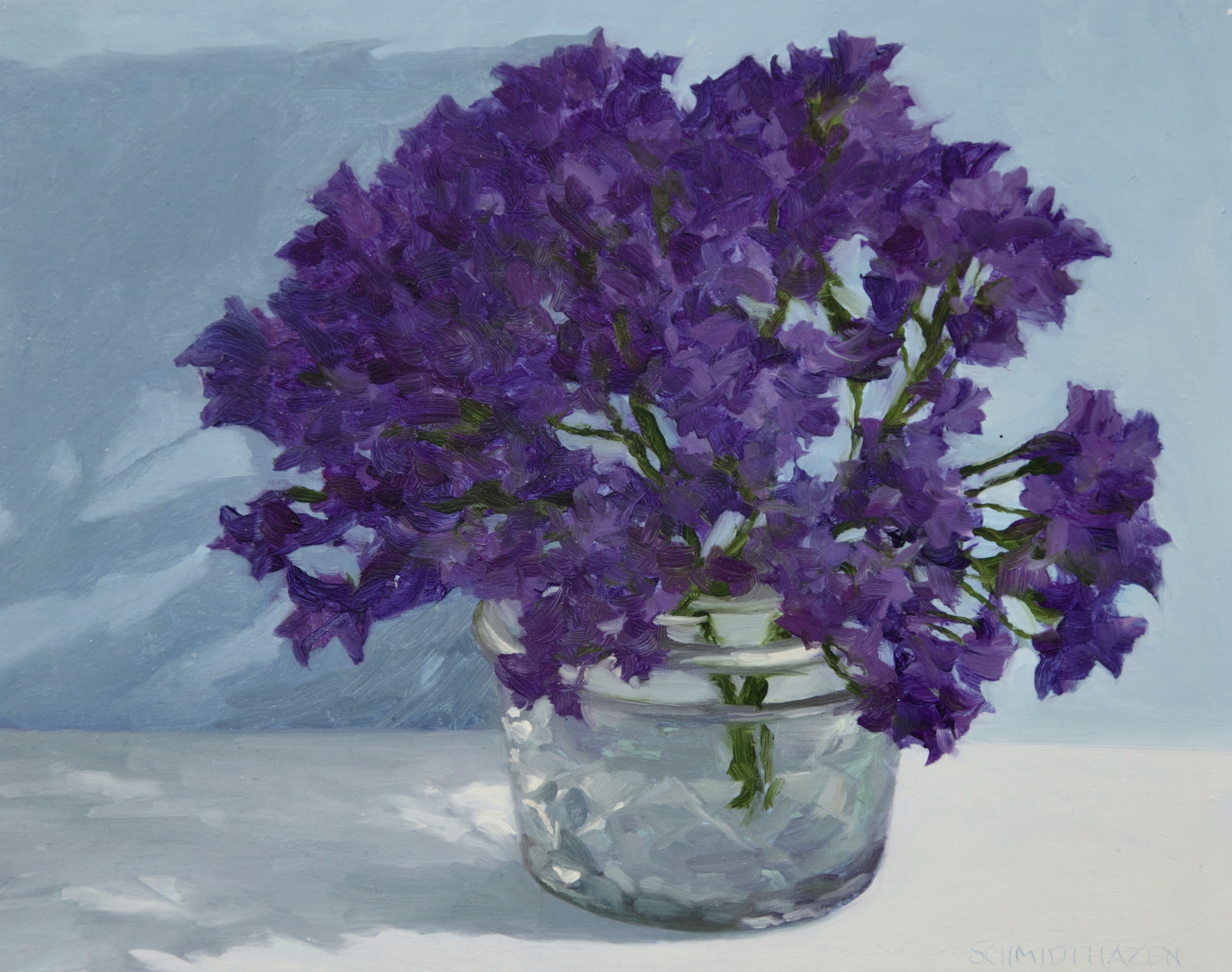 Small purple flowers in jelly jar with shadow and white cloth